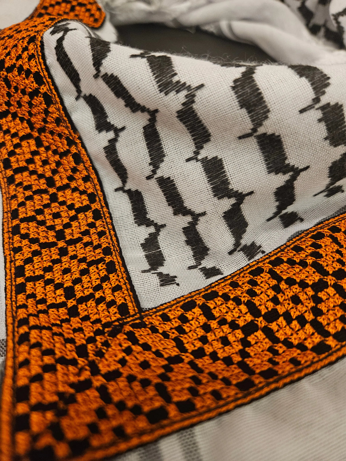 Close-up of a luxury gold keffiyeh bandana with detailed Tatreez embroidery, highlighting Palestinian heritage and intricate craftsmanship
