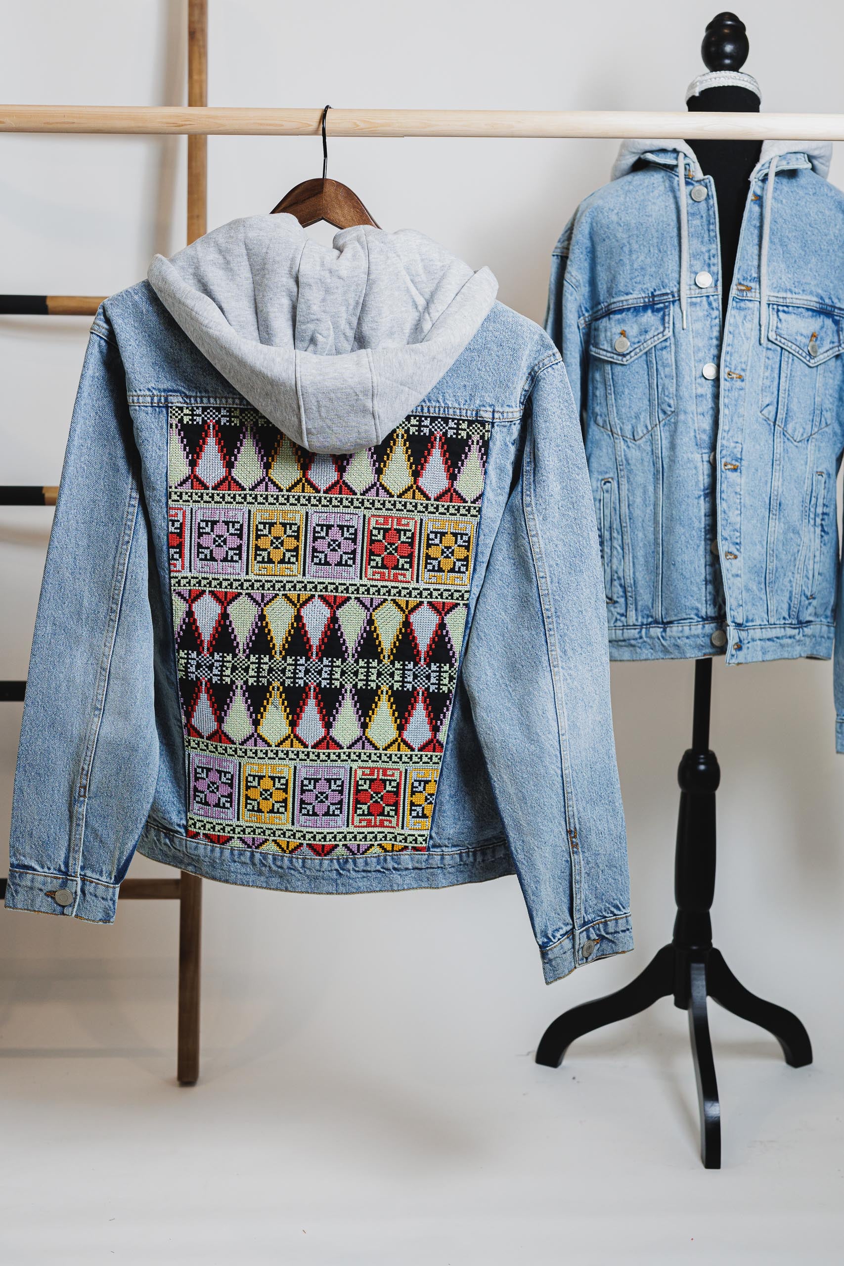 Embroidered blue unisex hooded denim jacket with Palestinian Tatreez design, showcasing modern streetwear.