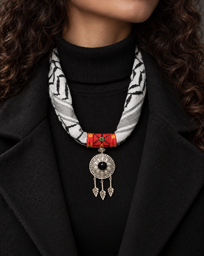 Woman wearing a Palestinian keffiyeh scarf necklace with red tatreez band and silver-tone medallion with black stone