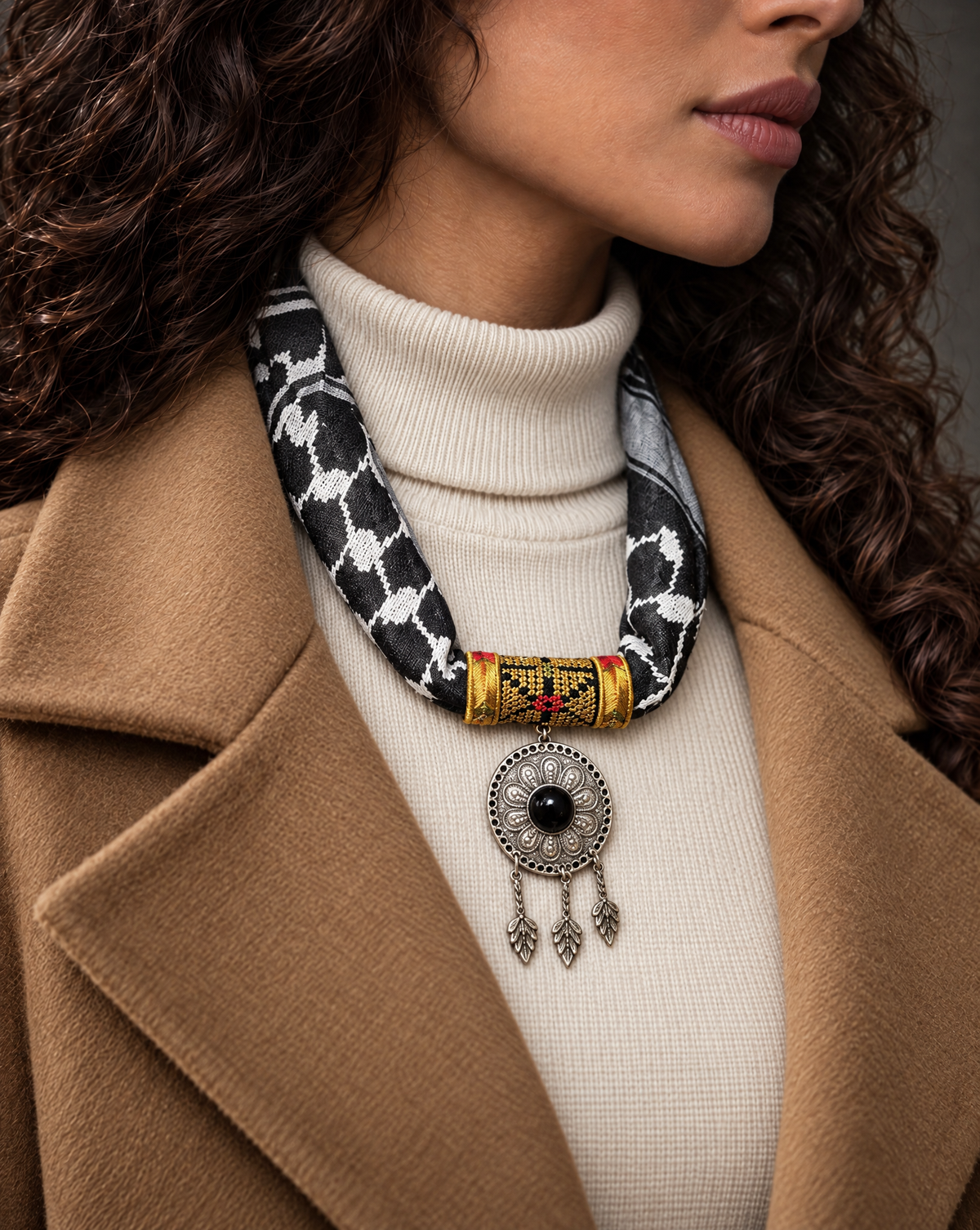Woman wearing a black keffiyeh scarf necklace with gold tatreez band and silver-tone medallion with black stone