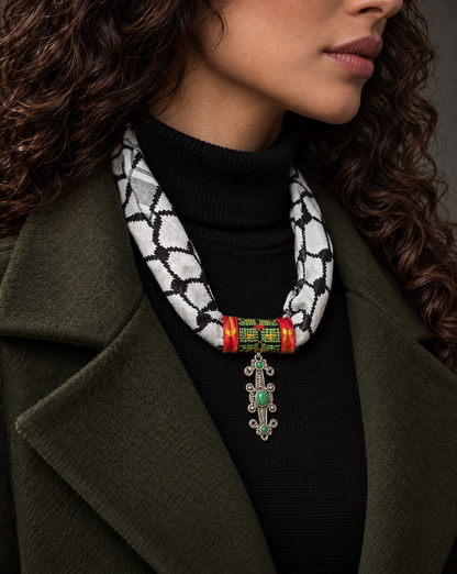 Woman wearing a Palestinian keffiyeh scarf necklace with green tatreez band and silver-tone pendant with green stones
