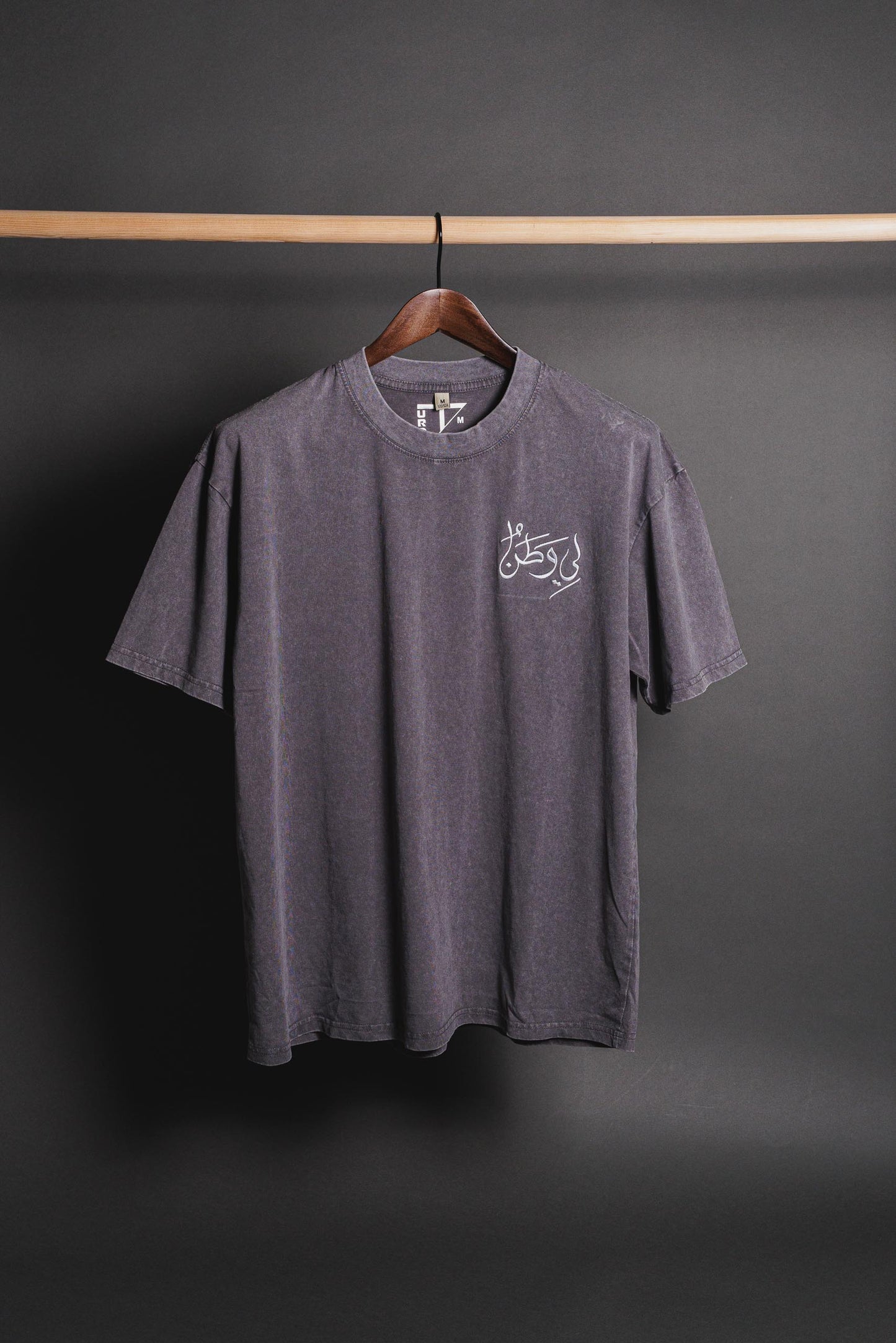 Gray Watan T-shirt with embroidered 'لي وطن' on the chest, positioned at the top right, symbolizing Palestinian heritage, pride, and cultural identity