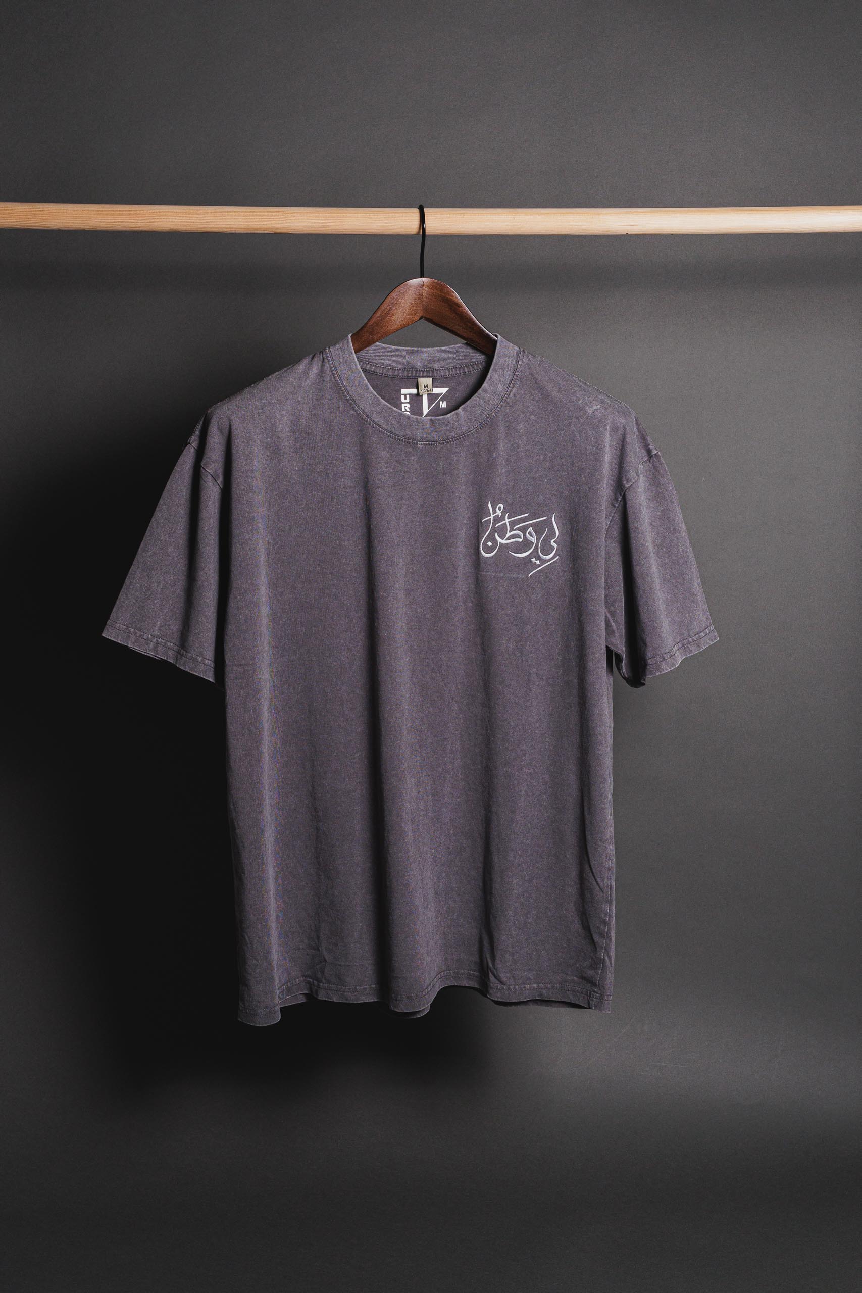 Gray Watan T-shirt with embroidered 'لي وطن' on the chest, positioned at the top right, symbolizing Palestinian heritage, pride, and cultural identity