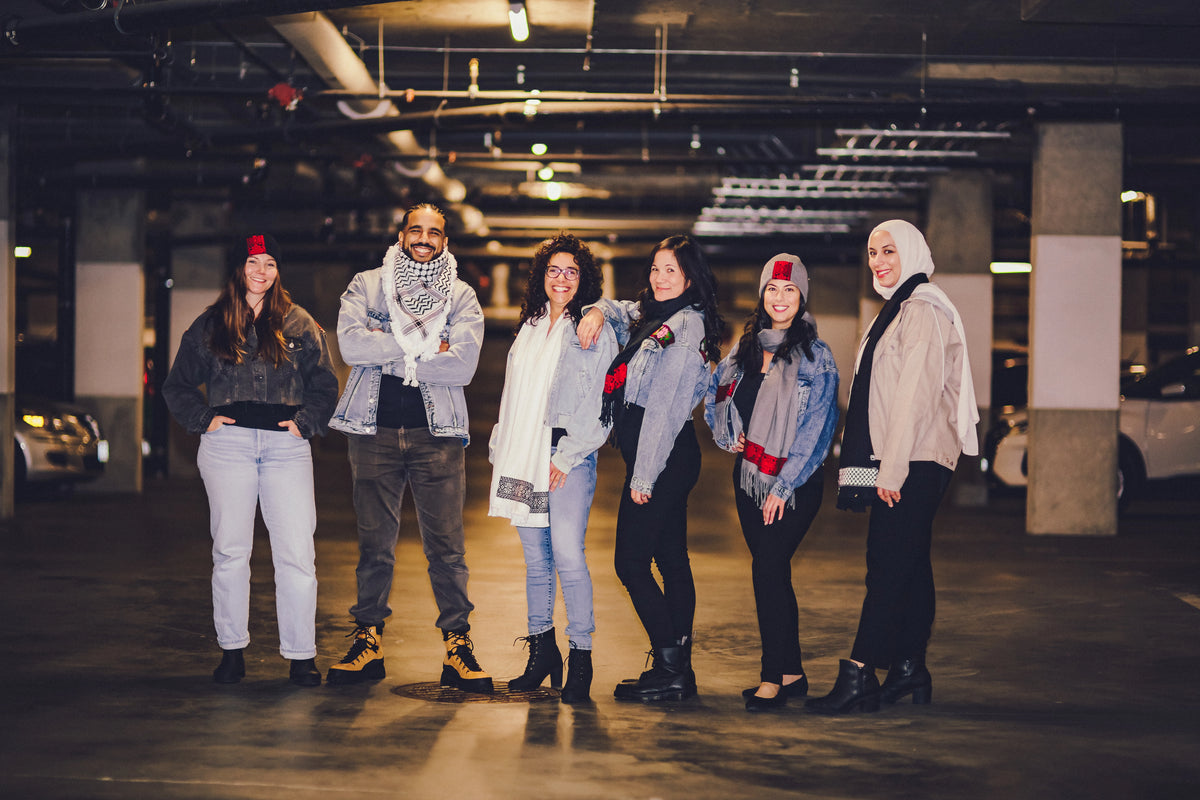 Group of six people posing together in a dimly lit parking garage.