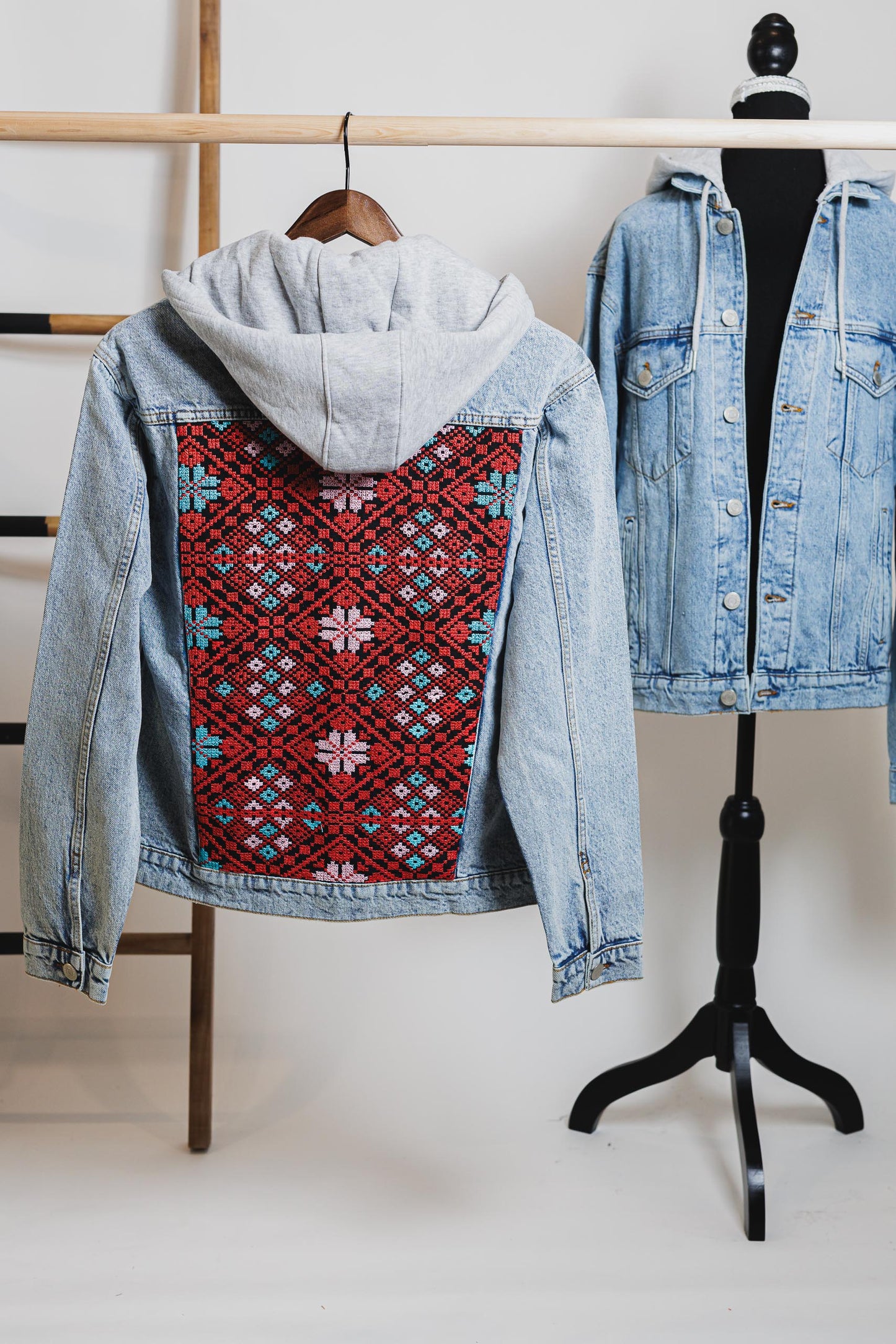 Two denim jackets on display, one with a visible embroidered design on the back, showcased on mannequins against a white background.