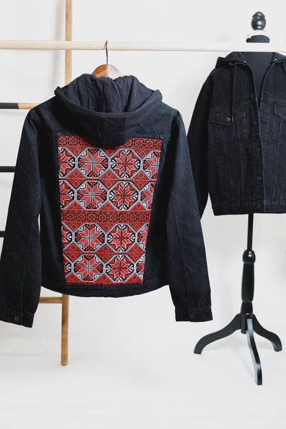 Black denim hooded jacket with vibrant Palestinian Tatreez embroidery on the back, showcasing traditional craftsmanship and cultural heritage