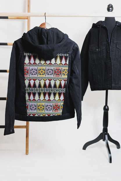 Black unisex denim jacket with colorful Tatreez embroidery on the back, showcasing vibrant Palestinian heritage and craftsmanship.