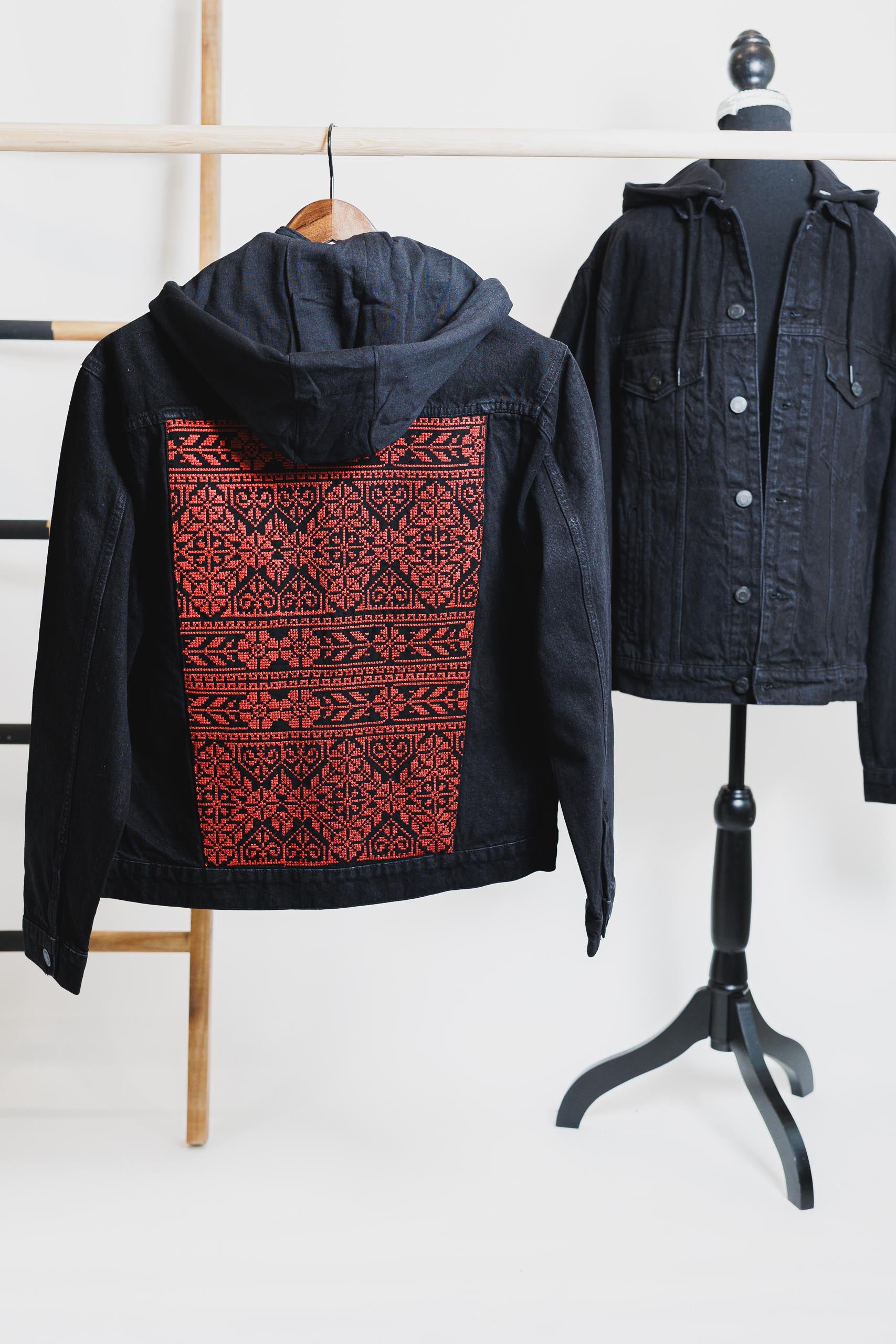 Black unisex denim jacket with red Tatreez embroidery on the back, showcasing Palestinian craftsmanship