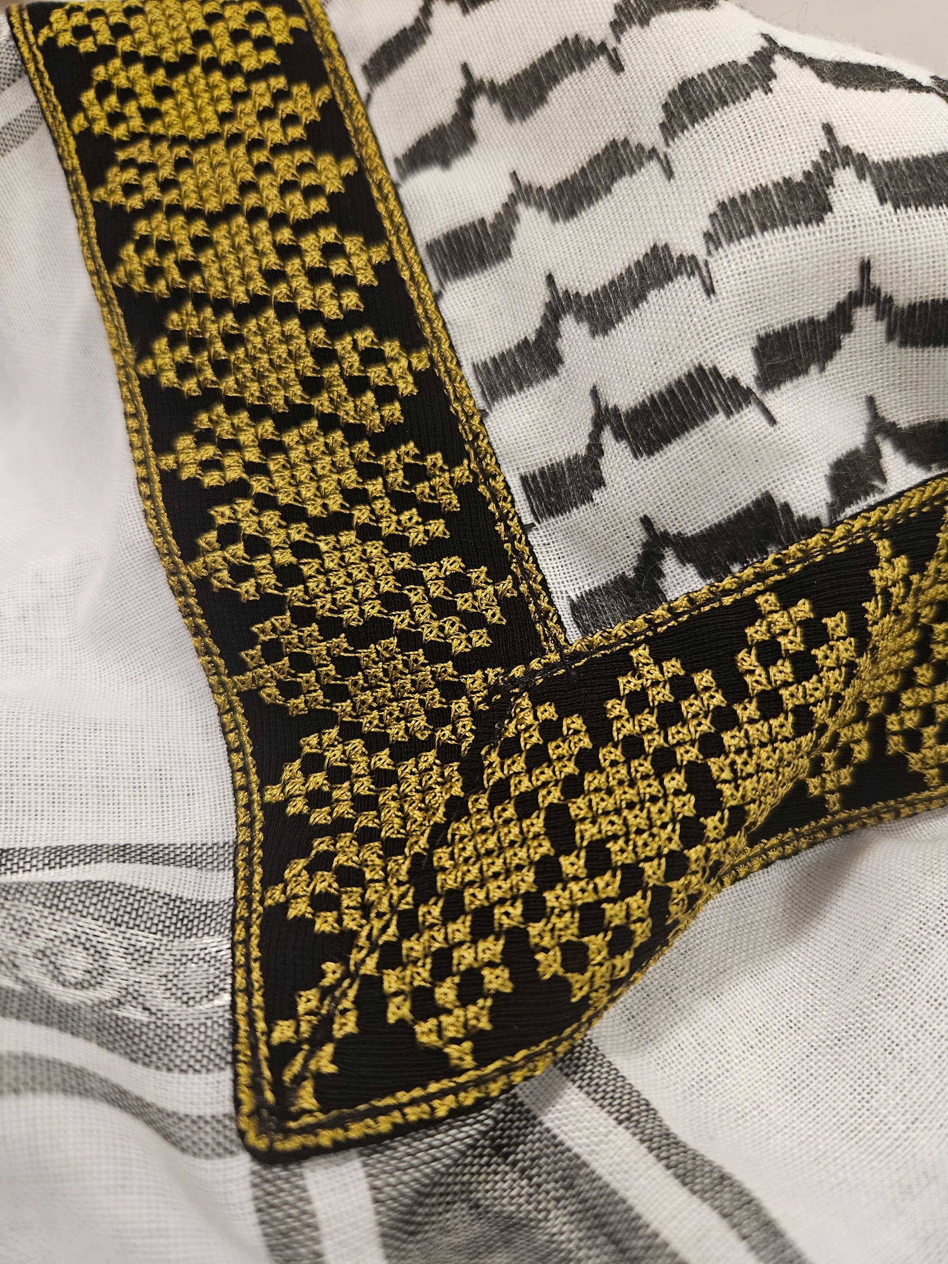 Close-up of a gold keffiyeh bandana with exquisite Tatreez embroidery, representing Palestinian heritage and traditional artistry.