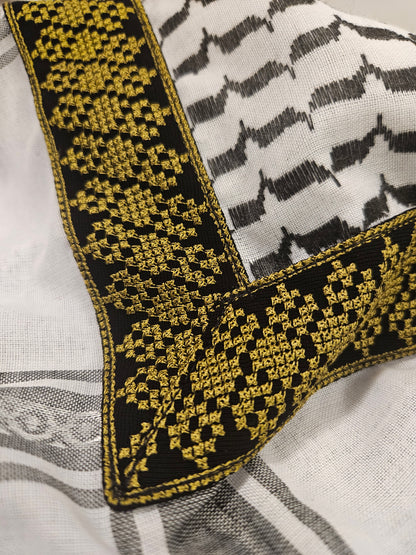 Close-up of a gold keffiyeh bandana with exquisite Tatreez embroidery, representing Palestinian heritage and traditional artistry.