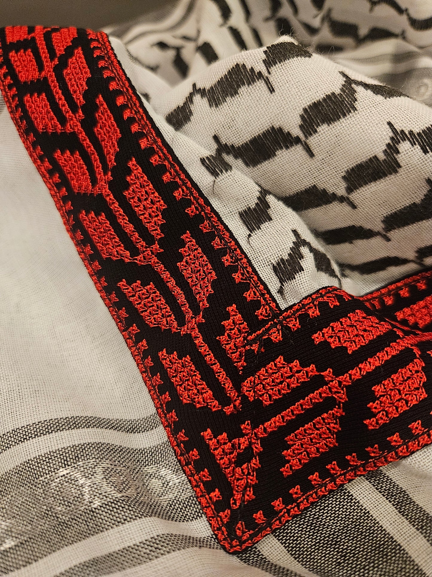 Close-up of a black and red keffiyeh bandana with traditional Tatreez embroidery, showcasing Palestinian heritage and cultural pride