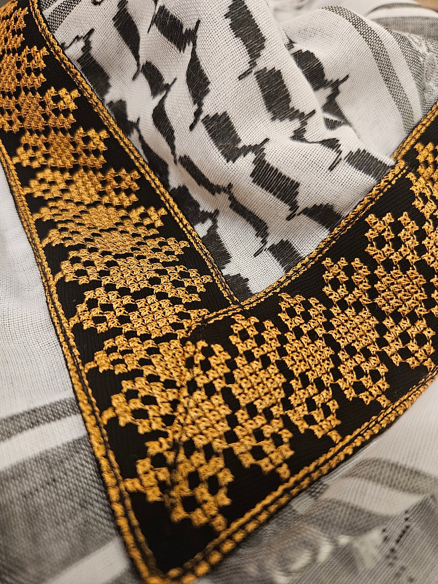 Close-up of a gold keffiyeh bandana with intricate Tatreez embroidery, showcasing Palestinian heritage and cultural craftsmanship