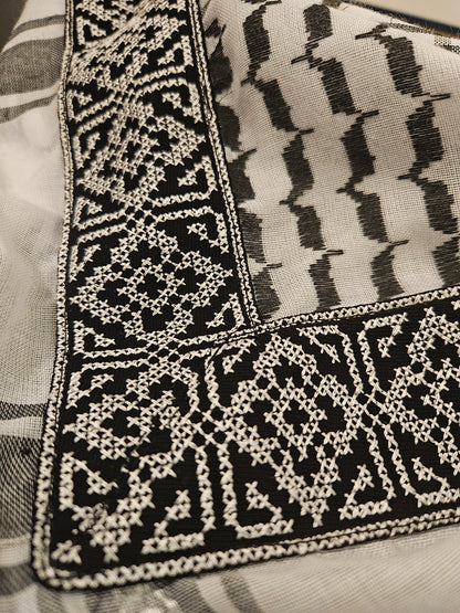 Close-up of a plain keffiyeh bandana with Tatreez embroidery, highlighting Palestinian craftsmanship and cultural heritage