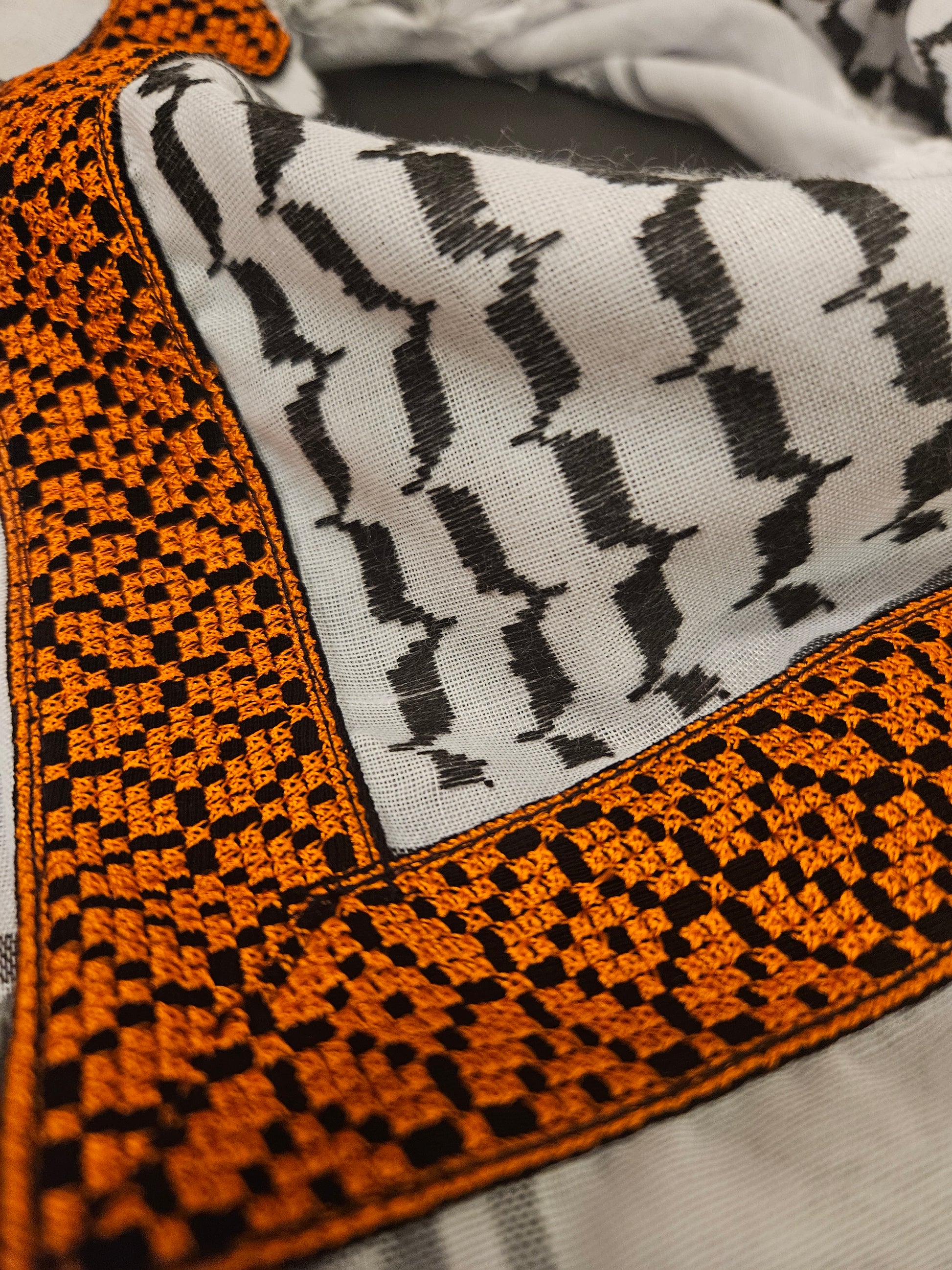 Close-up of a luxury gold keffiyeh bandana with detailed Tatreez embroidery, highlighting Palestinian heritage and intricate craftsmanship