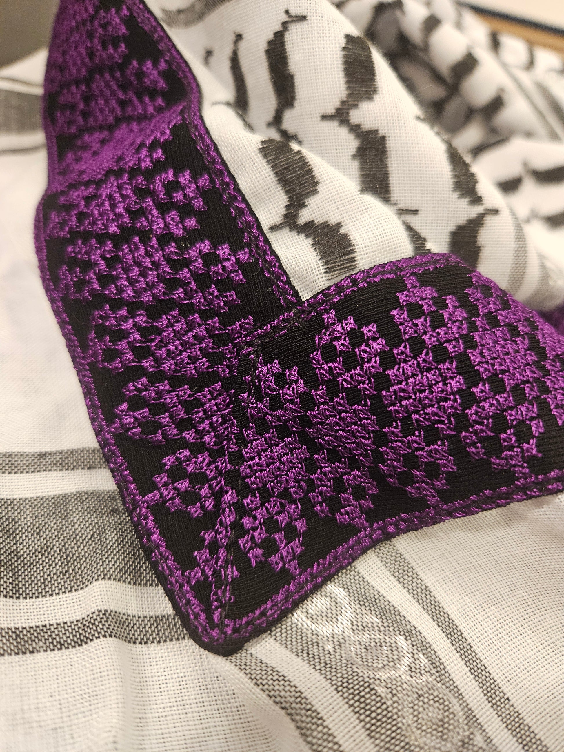 Close-up of a purple keffiyeh bandana featuring detailed Tatreez embroidery, showcasing Palestinian heritage and cultural pride.