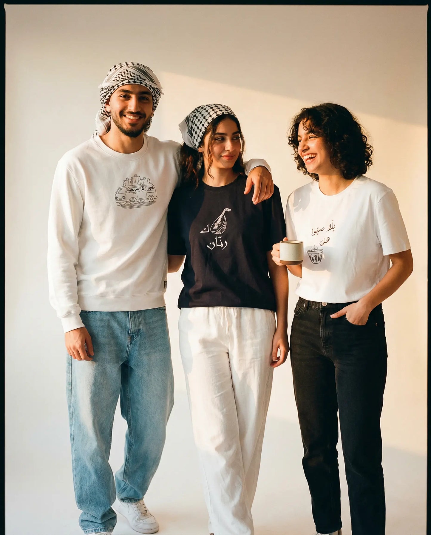 Three people standing together wearing branded clothing against a plain background