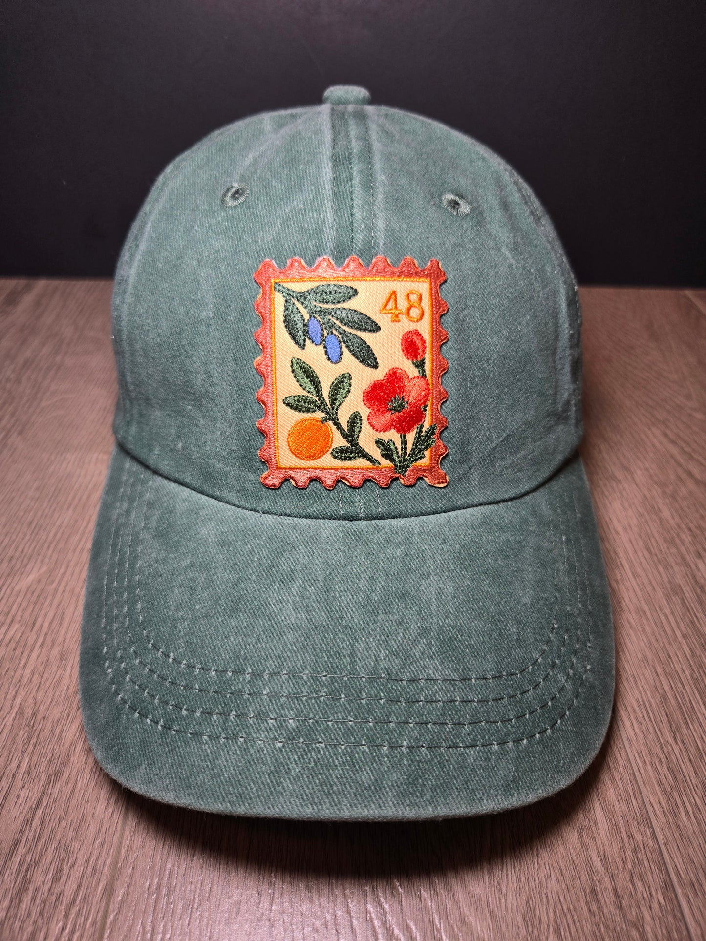 Green unisex cap with embroidered Palestine stamp and floral design, symbolizing cultural pride.