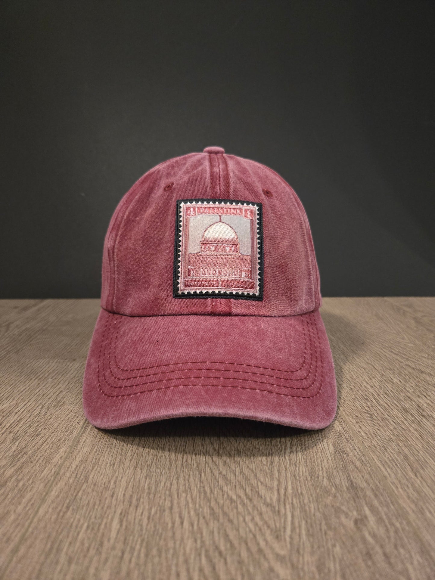 Unisex maroon washed cotton cap with embroidered Palestine stamp patch and adjustable strap.